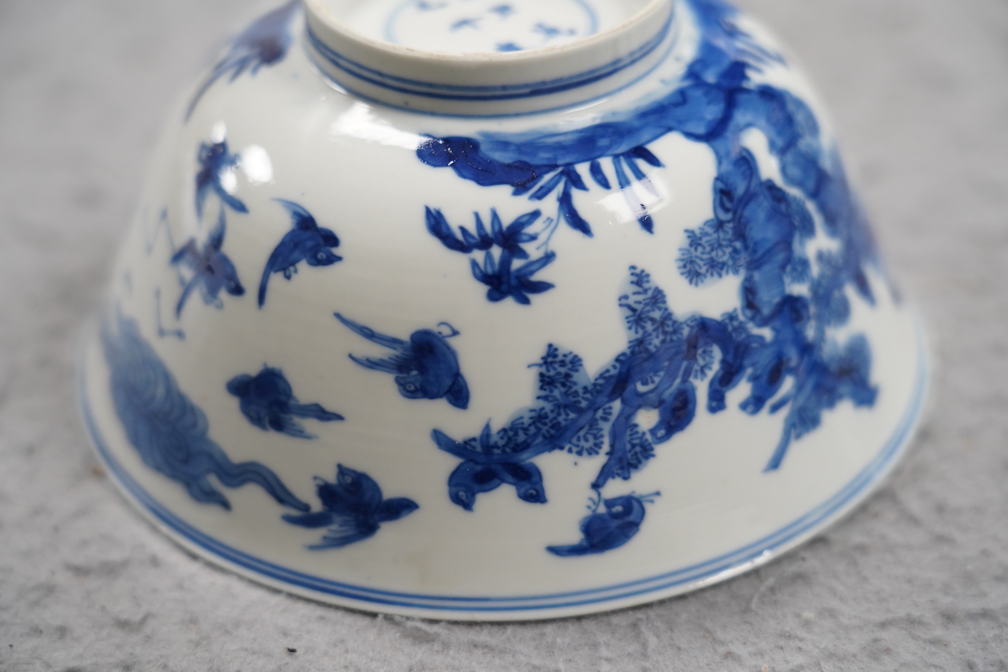 A near pair of Chinese blue and white ‘birds’ bowls, Kangxi period, one bowl restored